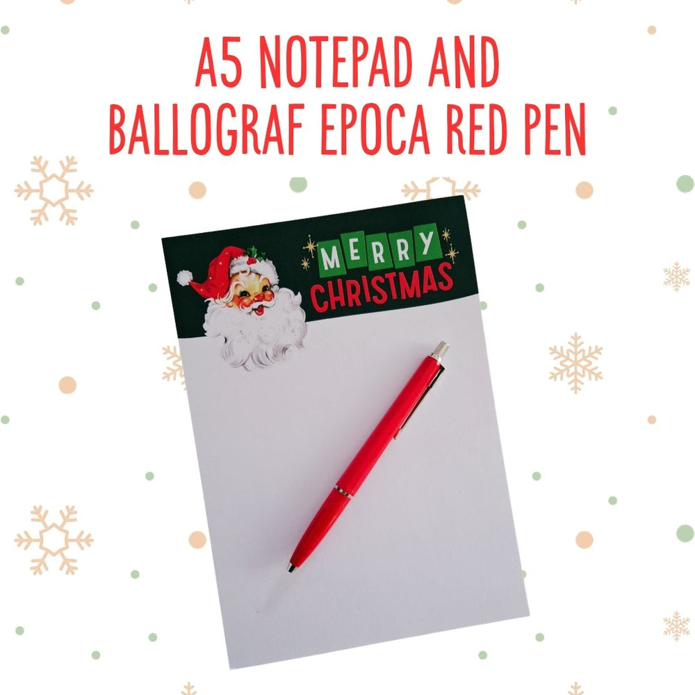 An A5 notepad with a Christmas Santa graphic and 'MERRY CHRISTMAS' header, paired with a red pen, shown on a white background with decorative snowflakes and the text 'A5 NOTEPAD AND BALLOGRAF EPOCA RED PEN'.
